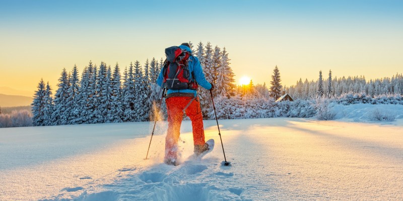 Snowshoe walker running in powder snow with beautiful sunrise light. Outdoor winter activity and healthy lifestyle