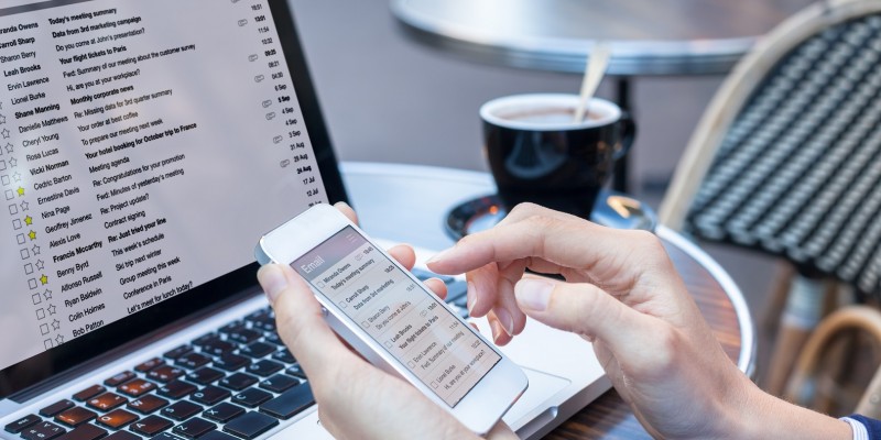 Business person reading emails on smartphone and laptop computer screen online, communication and marketing concept