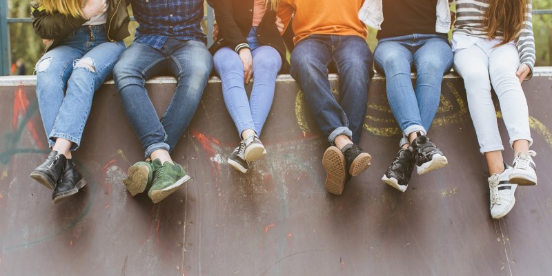 Summer holidays and teenage concept - group of smiling teenagers with skateboard hanging out outside.