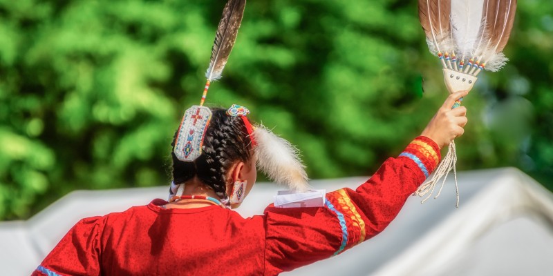 A closeup shot of the head of a person in a traditional Native Indian-American festive hat with feathers