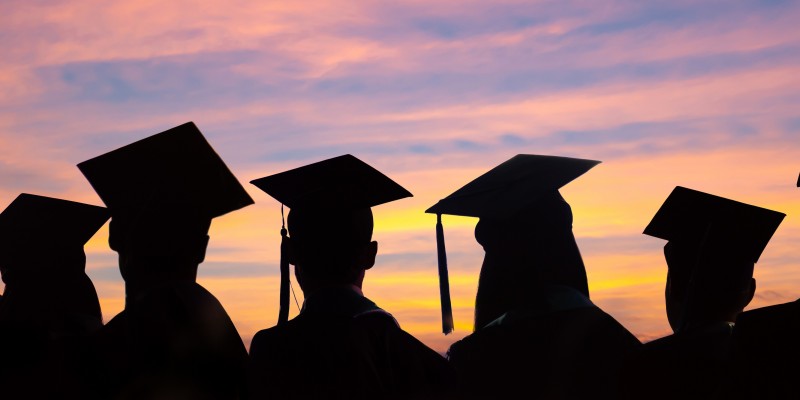 Silhouettes of students with graduate caps in a row on sunset background. Graduation ceremony at university web banner.