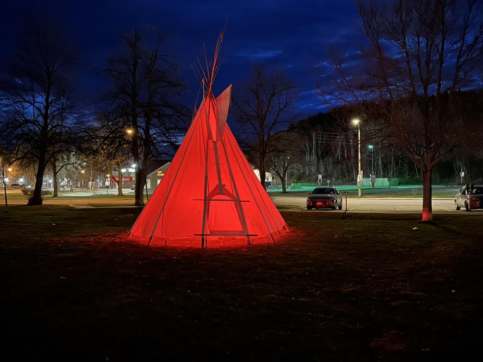 The tipi glows red on the Majestic Lawn, standing peacefully under the calm of a spring evening. Photo Credit: Ernest Green