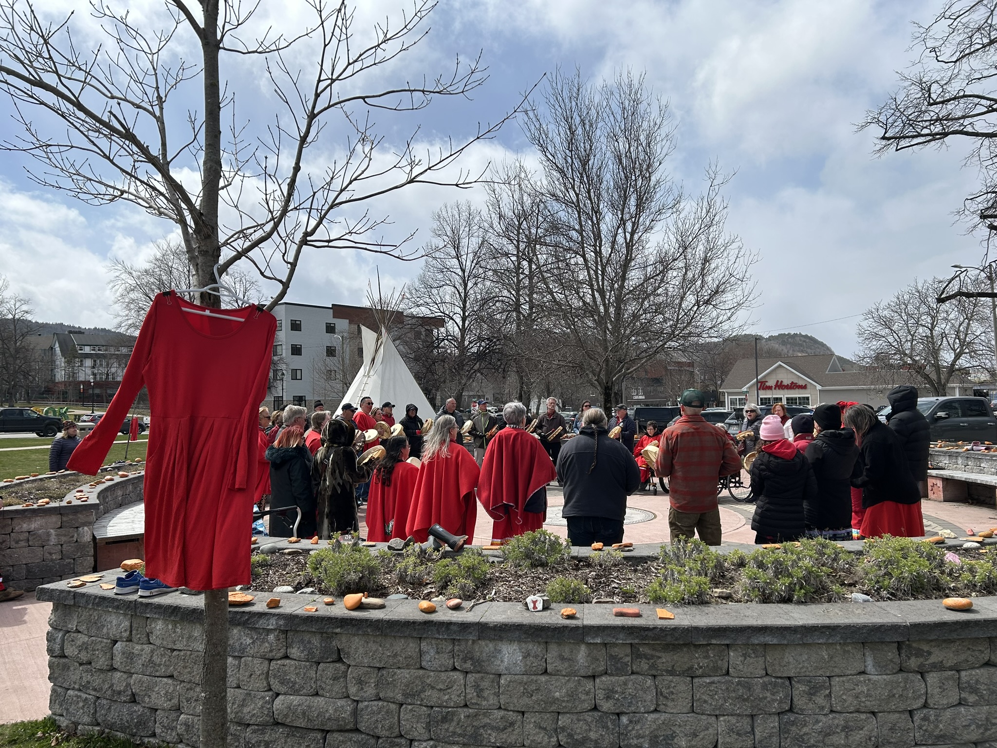 Musical sharing in the Mikwite’tm Garden, as red dresses sway in remembrance.